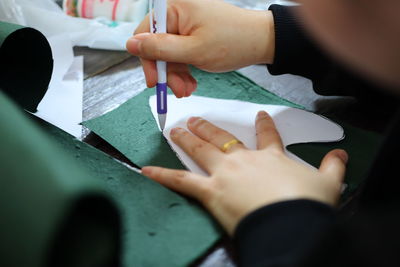 Cropped hands of person drawing with paper on table