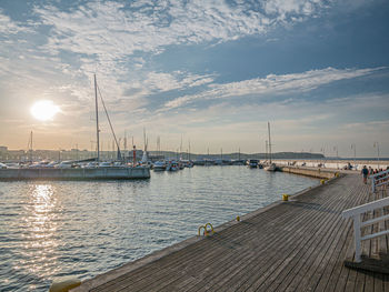 Sailboats moored at harbor against sky during sunset