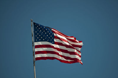 Low angle view of american flag against clear blue sky