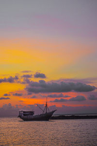 Sailboat in sea against sky during sunset