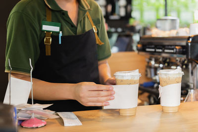 Barista serving ice coffee to customer in cafe coffee sho