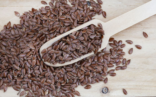 Linseed with wooden scoop on raw wooden table