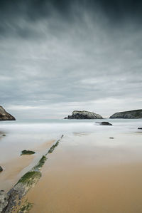 Scenic view of beach against cloudy sky