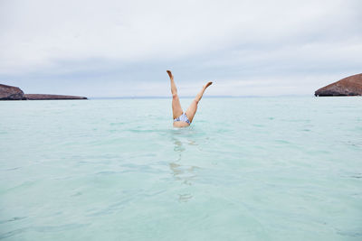 Low section of man in sea against sky