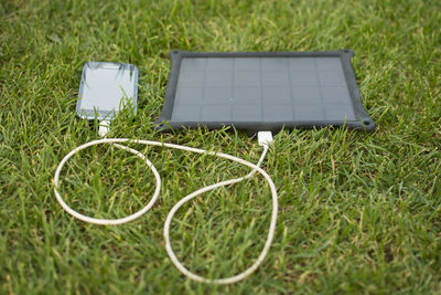 High angle view of smart phone getting charged on field