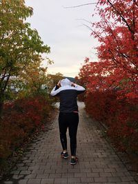 Rear view of woman walking on autumn leaves