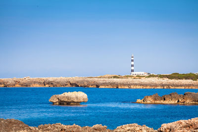 Lighthouse by sea against clear sky