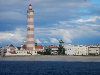 Lighthouse by sea against sky in city