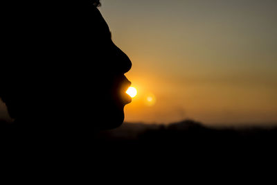 Close-up of silhouette hand against orange sky