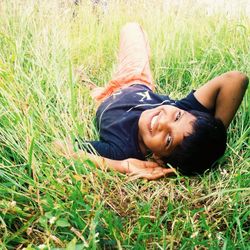 High angle portrait of smiling woman lying on land