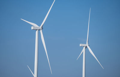 Low angle view of windmill against clear blue sky