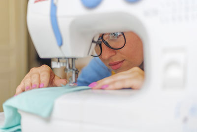 Cropped hand of woman using sewing machine