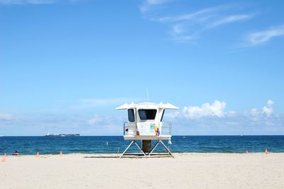 Lifeguard hut on beach against blue sky