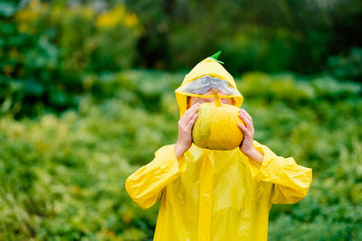 Boy in a yellow raincoat holds a yellow pumpkin. preparing for halloween. pumpkin harvest. 