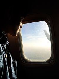 Close-up of man looking through airplane window