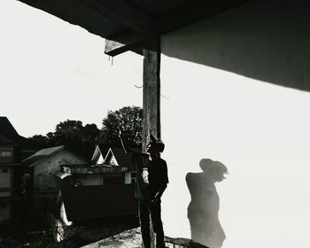 Silhouette people standing by building against sky