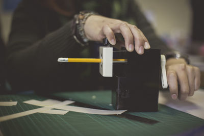 Midsection of female student sharpening pencil at desk