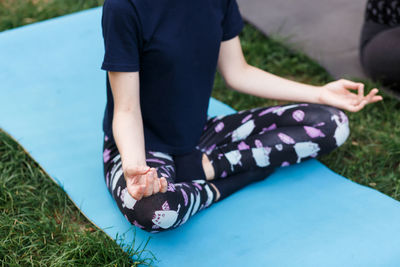 The relaxed girl is doing yoga in the park on carpet