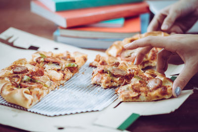 Close-up of hand holding pizza on table