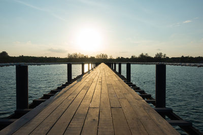 Pier over lake against sky during sunset