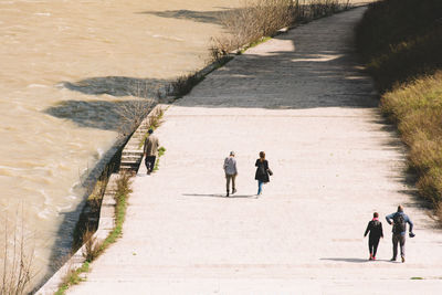 High angle view of people walking on footpath by river