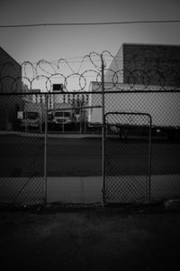 Fence by building against sky