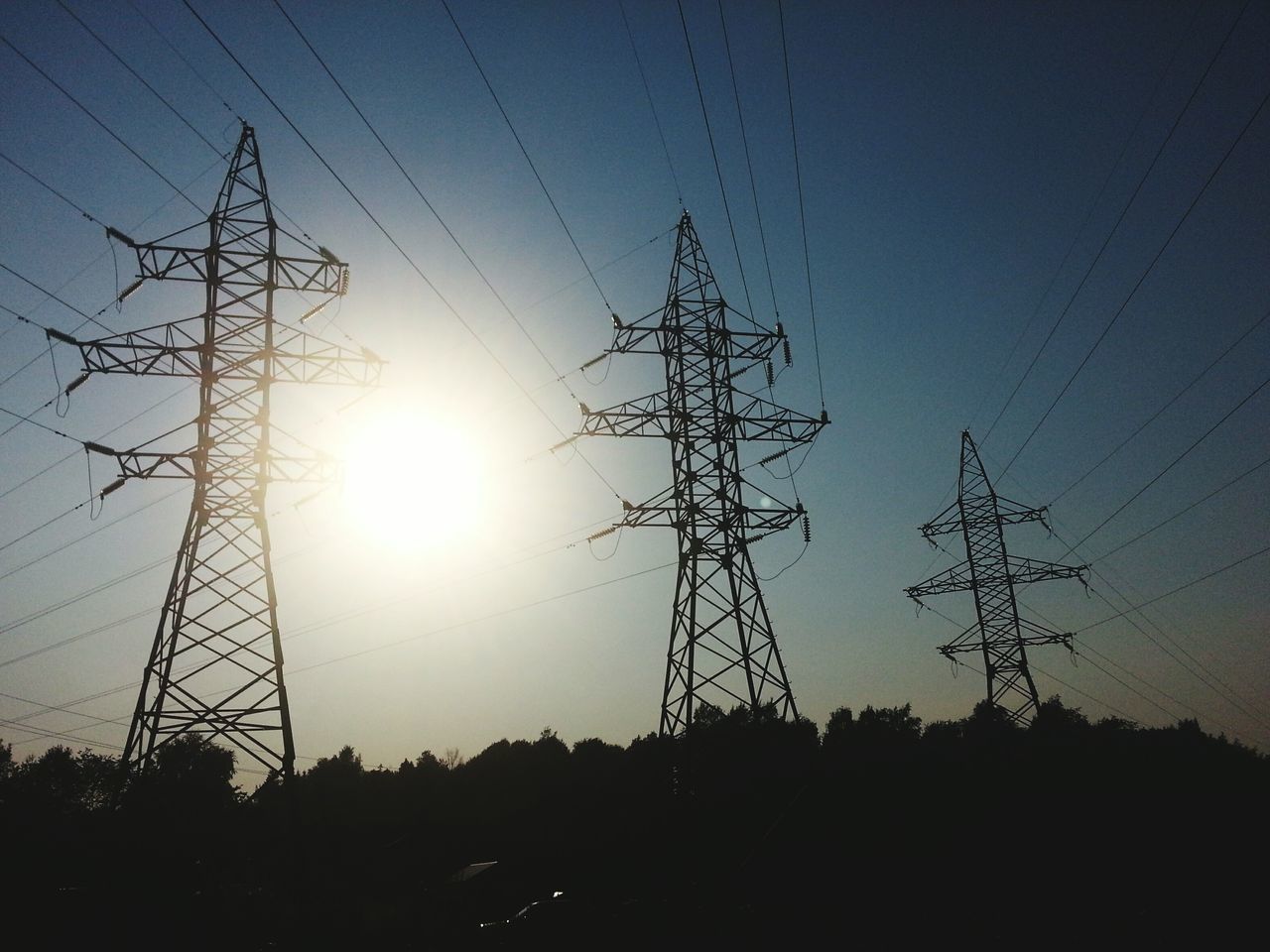 electricity pylon, power line, silhouette, electricity, power supply, sunset, fuel and power generation, sun, connection, technology, cable, low angle view, sky, power cable, sunlight, nature, outdoors, no people, complexity, lens flare