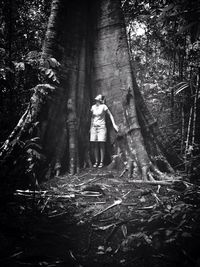 Woman standing on tree trunk in forest