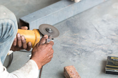 High angle view of worker grinding metal while working in workshop