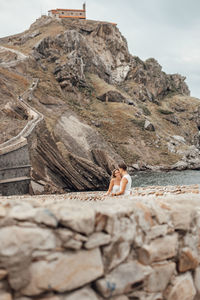 Rear view of couple sitting on rock