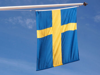 Low angle view of flag against blue sky