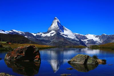 Scenic view of lake and mountains against clear blue sky