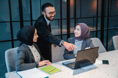 Portrait of young woman using laptop at office