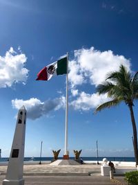 Low angle view of mexican flag against cloudy sky