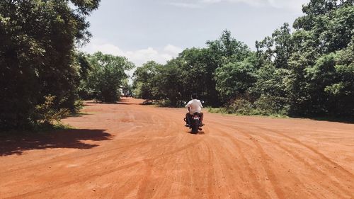 Rear view of man riding motorcycle on road