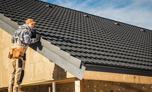 Low angle view of man climbing on roof