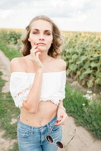 A young girl with a model appearance, in denim trousers and a white blouse in a sunflower field