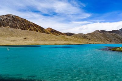 Scenic view of sea and mountains against blue sky