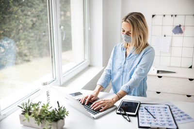 Businesswoman wearing mask while using laptop at office