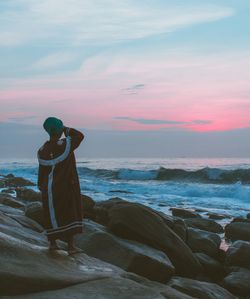 Woman standing on beach at sunset