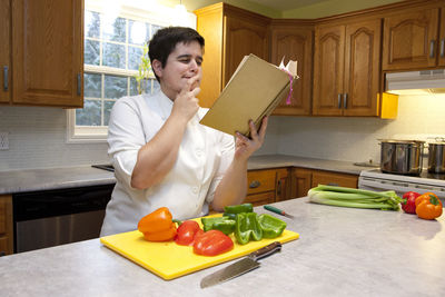 Woman reading at cookbook at kitchen