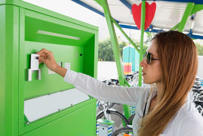 Businesswoman using machinery at bicycle sharing system