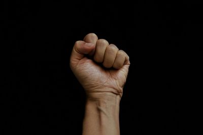 Cropped image of clenched fist against black background