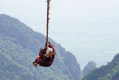 Rear view of woman on akha swing against mountain