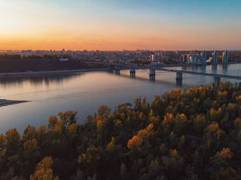 High angle view of river by buildings against sky during sunset