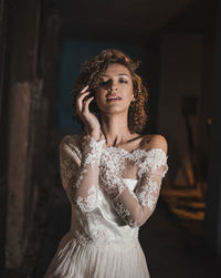 Portrait of sensuous woman in wedding dress standing at home