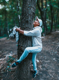Full length of man standing by tree trunk in forest