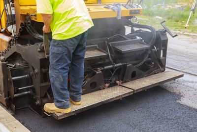 Low section of man operating construction machinery on road 