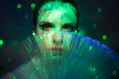 Close-up portrait of young woman against illuminated background