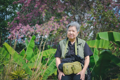 Portrait of senior woman sitting against plants